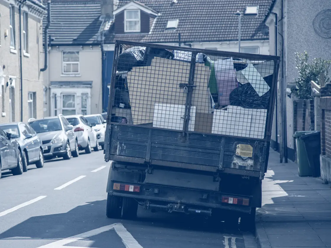 A clearance tipper loaded with household waste on a terraced street