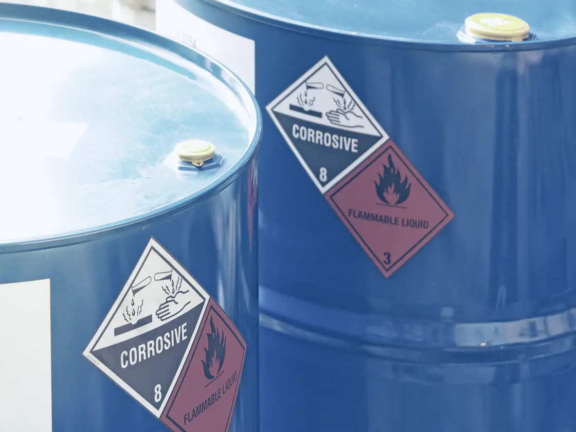 Blue drums of hazardous waste, corrosive and flammable-liquid diamonds showing