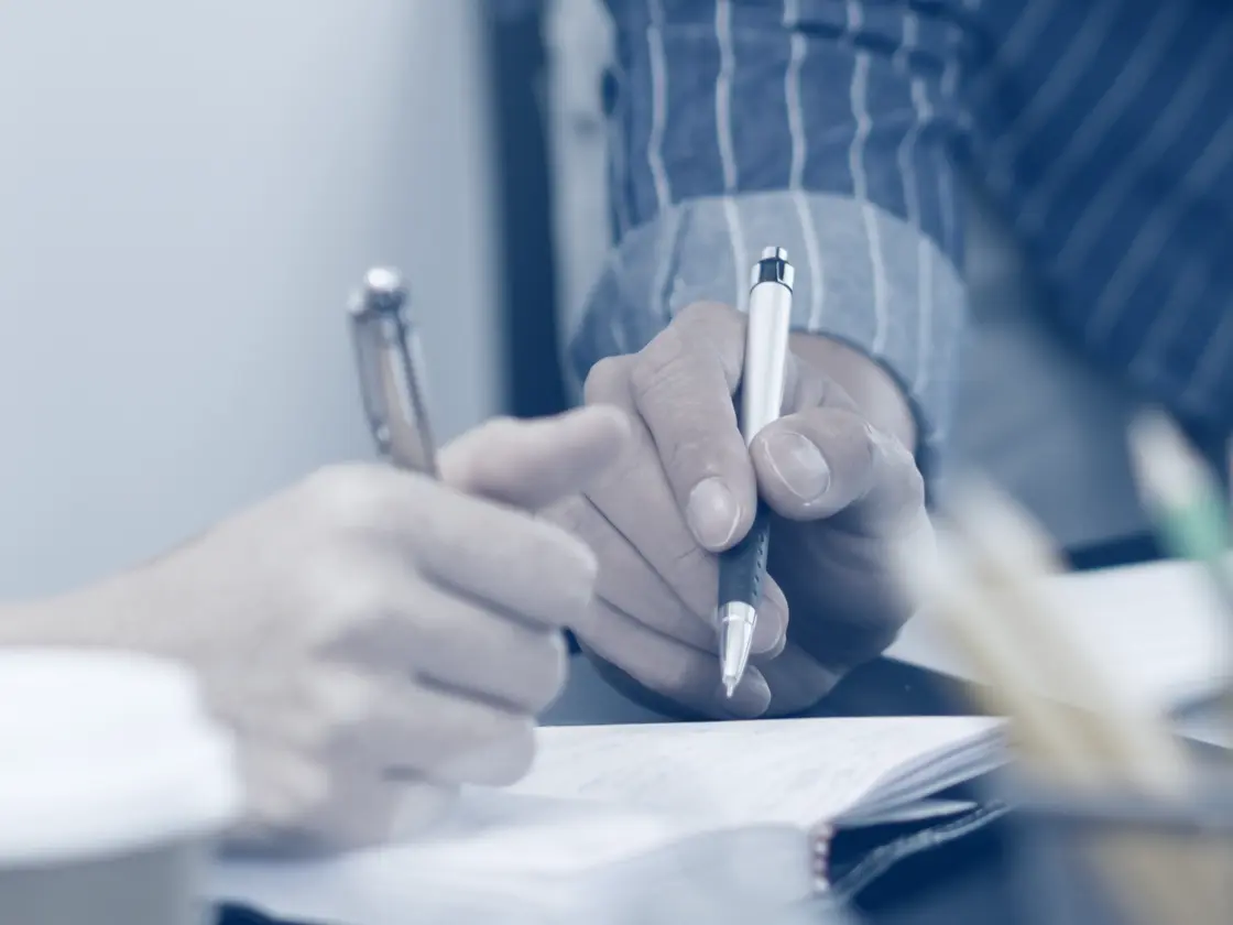 Two people at one desk working through a set-up, pen in hand